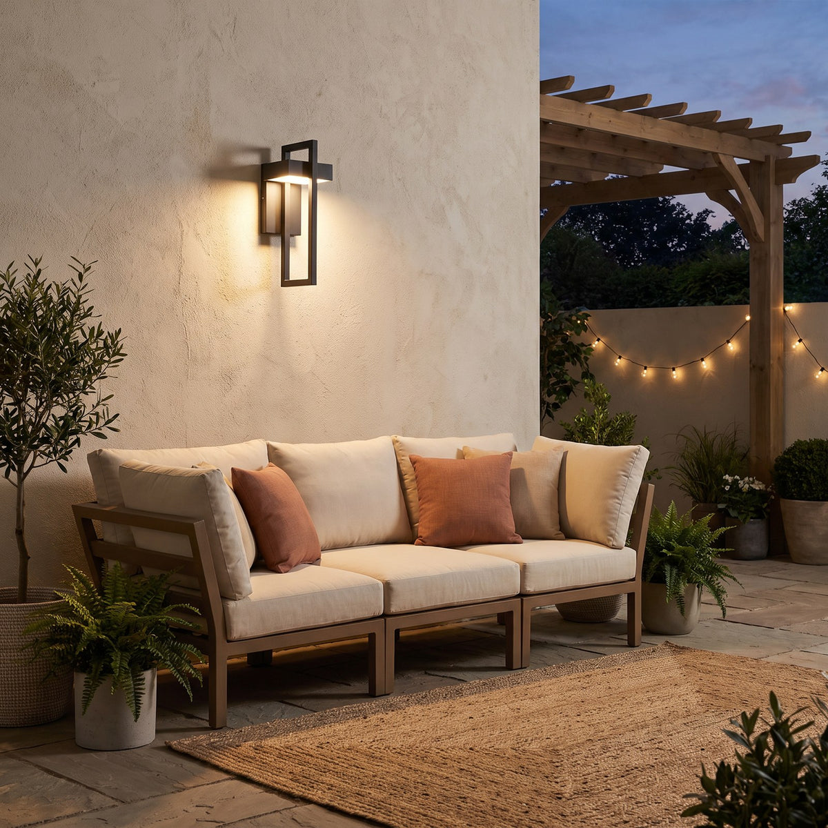 Modern black outdoor wall light above a patio sofa in the evening